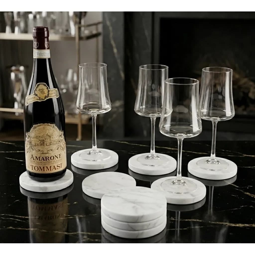 Jogo de porta-copos redondos de mármore branco com veios cinza, sob taças de vinho em bancada de mármore preto